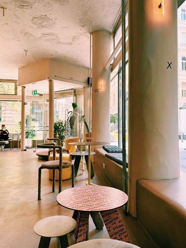 Интерьер Café Arkitekter — колонны, фирменные розовые столики и большие окна
