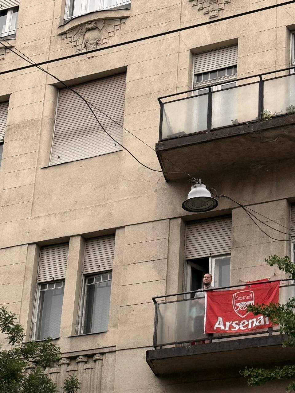 Болельщик Арсенала с флагом на балконе жилого дома в Будапеште